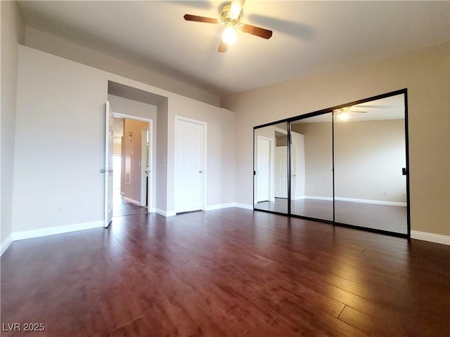 unfurnished bedroom featuring wood finished floors, baseboards, a closet, and ceiling fan