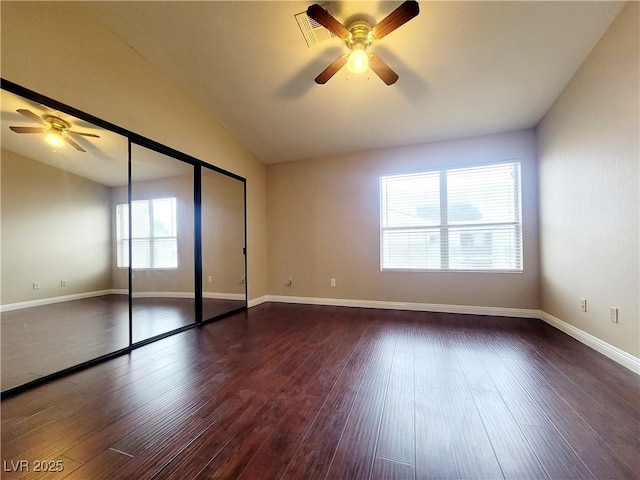 unfurnished bedroom with baseboards, ceiling fan, a closet, lofted ceiling, and dark wood-style floors