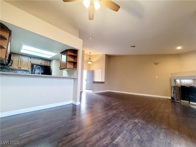 unfurnished living room featuring a sink, baseboards, dark wood-type flooring, and a ceiling fan