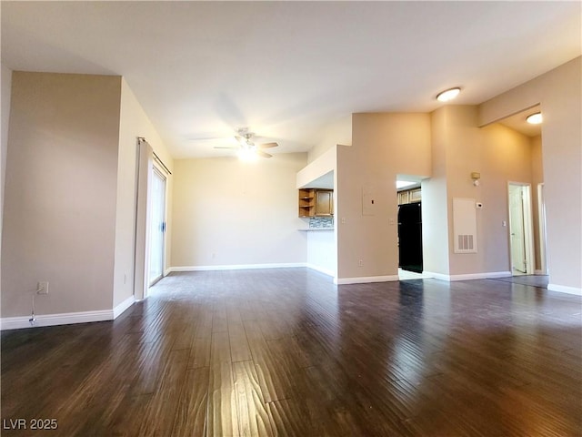 unfurnished living room with dark wood-style floors, visible vents, baseboards, ceiling fan, and vaulted ceiling