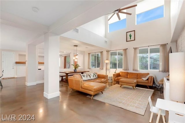 living room with visible vents, a ceiling fan, concrete floors, baseboards, and a towering ceiling