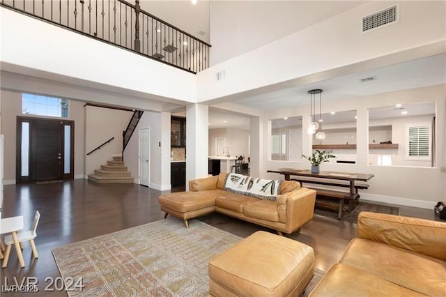 living room featuring visible vents, baseboards, a high ceiling, and stairs