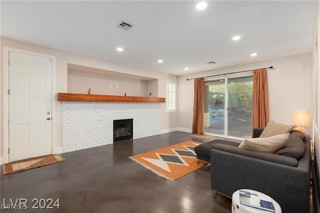 living area featuring visible vents, recessed lighting, a brick fireplace, and concrete flooring