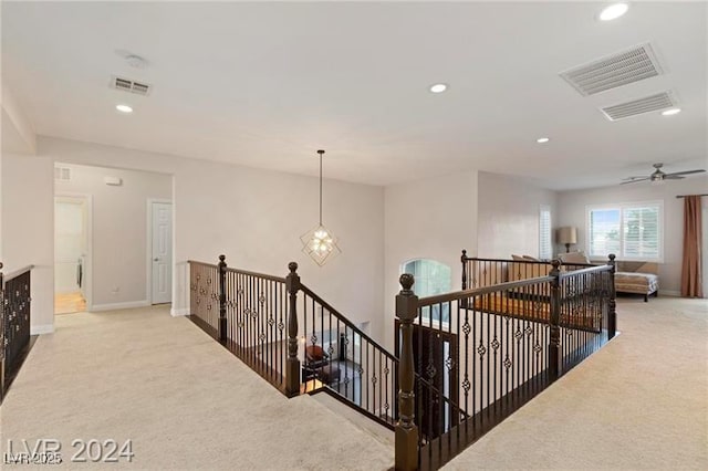 hallway with recessed lighting, visible vents, an upstairs landing, and light colored carpet