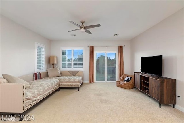 living area featuring visible vents, light colored carpet, baseboards, and a ceiling fan