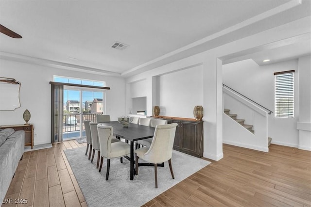 dining area featuring visible vents, baseboards, light wood-style floors, and stairs