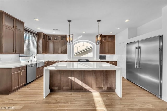 kitchen featuring a sink, stainless steel appliances, glass insert cabinets, and light countertops