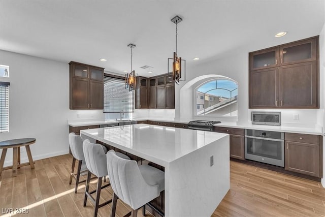 kitchen featuring a sink, light wood-style flooring, appliances with stainless steel finishes, and a wealth of natural light