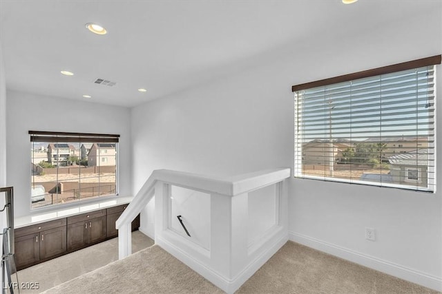 interior space featuring visible vents, an upstairs landing, recessed lighting, baseboards, and light colored carpet