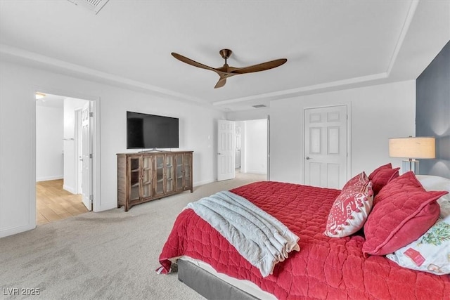 carpeted bedroom with a ceiling fan, a tray ceiling, and baseboards