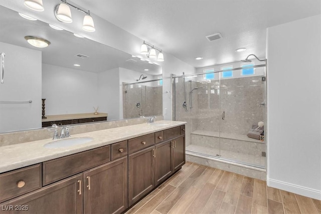 bathroom featuring a sink, visible vents, a shower stall, and wood tiled floor