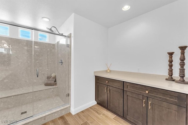 full bathroom featuring wood finish floors, baseboards, a stall shower, and recessed lighting