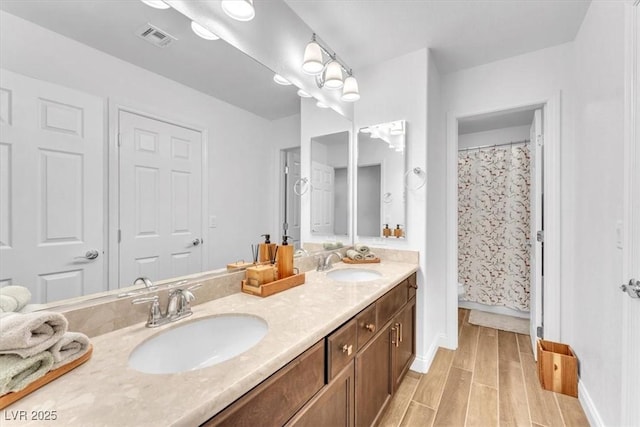 full bathroom featuring a sink, visible vents, double vanity, and wood tiled floor