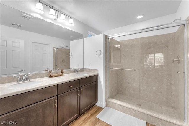 full bathroom featuring a sink, visible vents, a stall shower, and wood finished floors