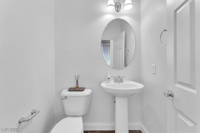 bathroom featuring a sink, baseboards, and toilet