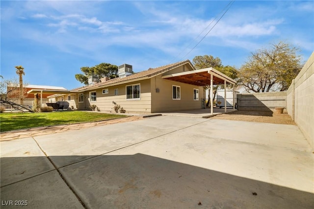 exterior space featuring a carport, concrete driveway, a fenced backyard, and a front lawn