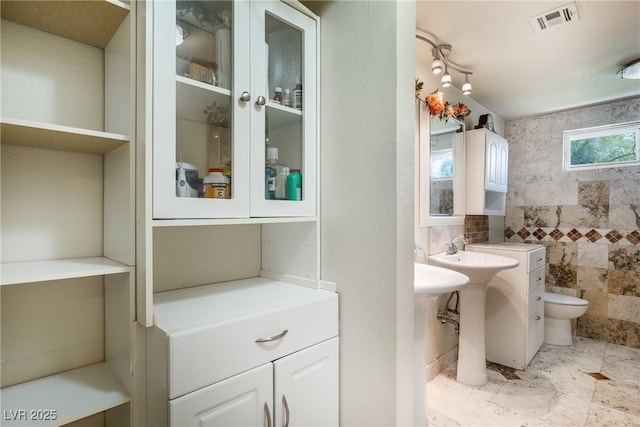 full bathroom featuring tile walls, toilet, and visible vents