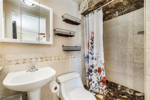 full bath with tile walls, toilet, a tile shower, and a sink