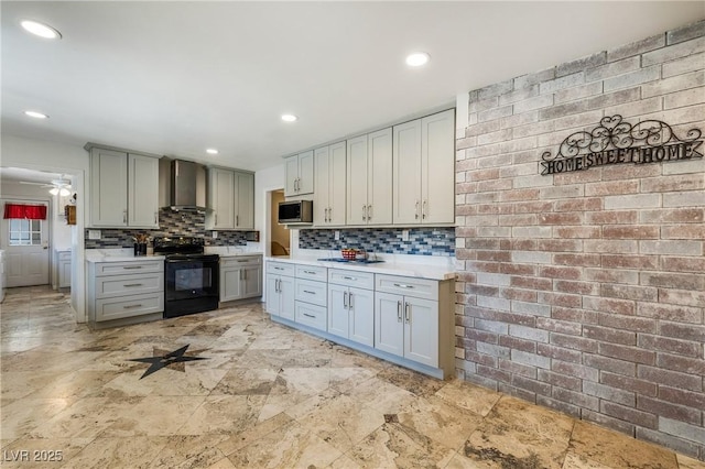 kitchen featuring gray cabinets, light countertops, stainless steel microwave, wall chimney exhaust hood, and black electric range oven