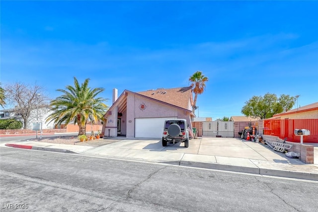 view of front of property with fence, concrete driveway, stucco siding, an attached garage, and a gate