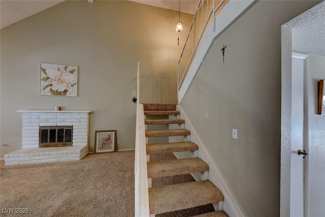 stairway with carpet floors, high vaulted ceiling, and a fireplace