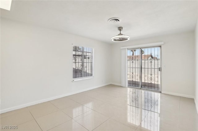 unfurnished room featuring tile patterned floors, visible vents, and baseboards