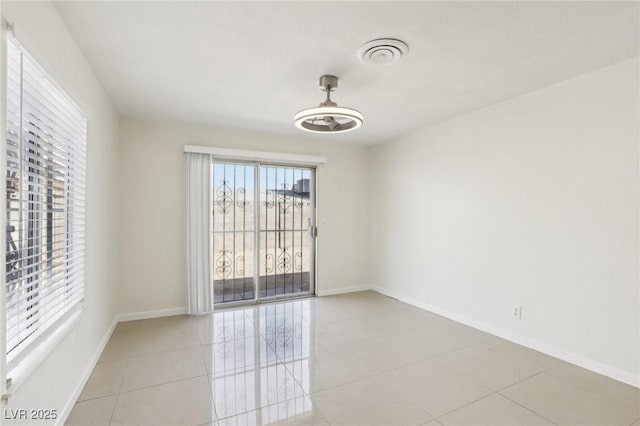 unfurnished room featuring light tile patterned floors, visible vents, and baseboards