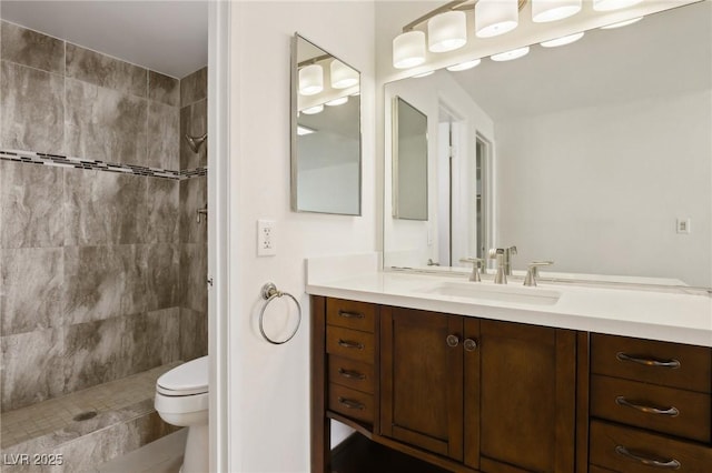 bathroom with vanity, toilet, and tiled shower