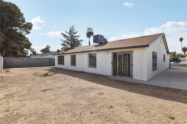 rear view of house with central AC unit, stucco siding, and fence private yard