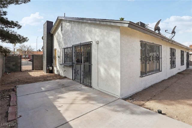 view of home's exterior with a gate, a patio area, stucco siding, and fence