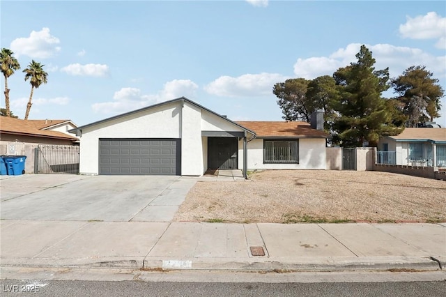 view of front of home with stucco siding, a gate, fence, concrete driveway, and a garage