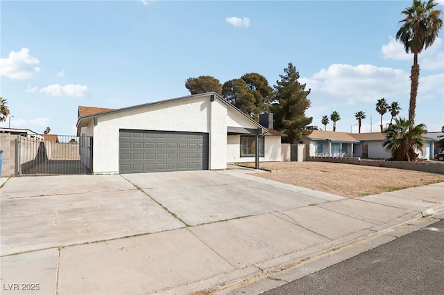 view of front of house with stucco siding, a garage, driveway, and fence