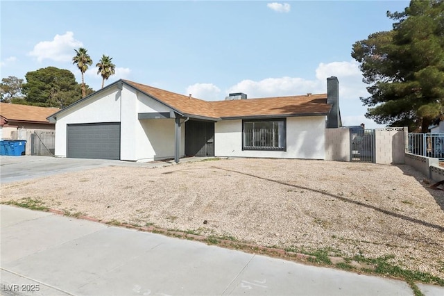 ranch-style house with a gate, an attached garage, driveway, and stucco siding