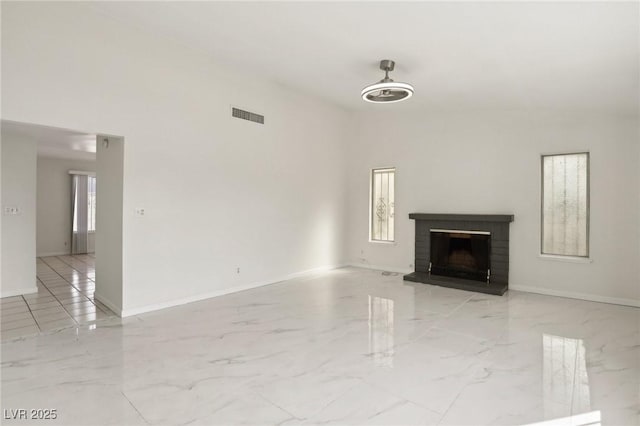 unfurnished living room featuring a fireplace, visible vents, marble finish floor, and baseboards