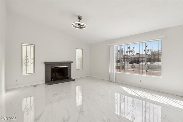 unfurnished living room featuring lofted ceiling, a brick fireplace, baseboards, and marble finish floor