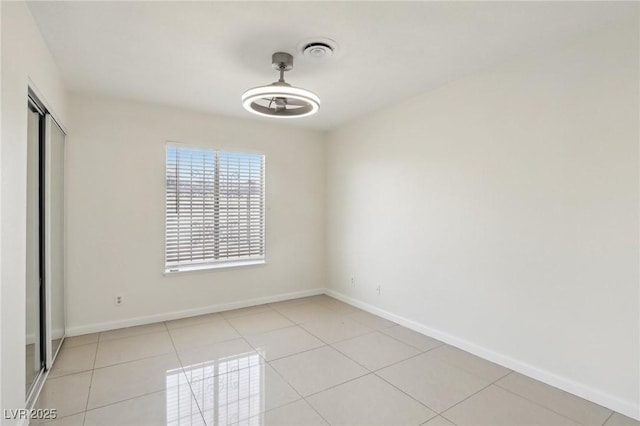 empty room with light tile patterned floors, visible vents, and baseboards