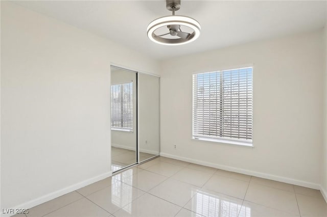 unfurnished bedroom with tile patterned flooring, baseboards, and a closet