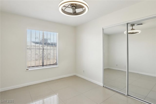 unfurnished bedroom with tile patterned flooring, baseboards, and a closet