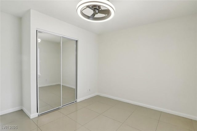 unfurnished bedroom with light tile patterned floors, baseboards, and a closet