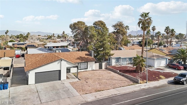 ranch-style house with an attached garage, fence, a residential view, concrete driveway, and a mountain view