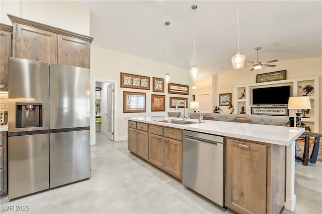 kitchen featuring a kitchen island with sink, a sink, appliances with stainless steel finishes, light countertops, and lofted ceiling