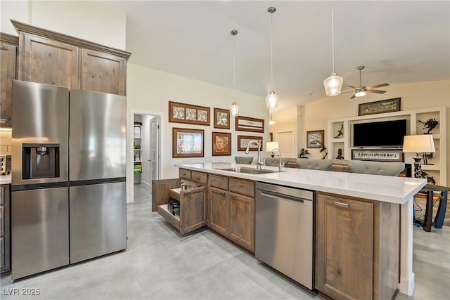 kitchen featuring a sink, light countertops, appliances with stainless steel finishes, decorative light fixtures, and open floor plan