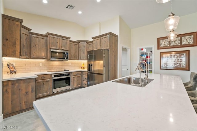 kitchen with backsplash, pendant lighting, recessed lighting, appliances with stainless steel finishes, and a sink