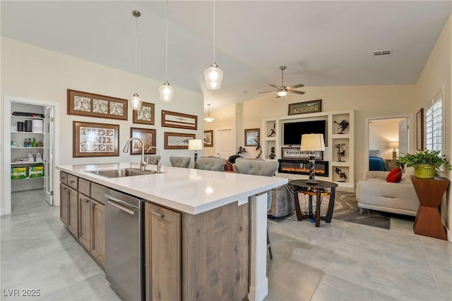 kitchen featuring visible vents, open floor plan, dishwasher, a glass covered fireplace, and a sink