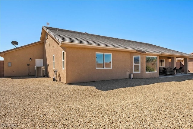 rear view of house with a patio area, stucco siding, a tiled roof, and central AC