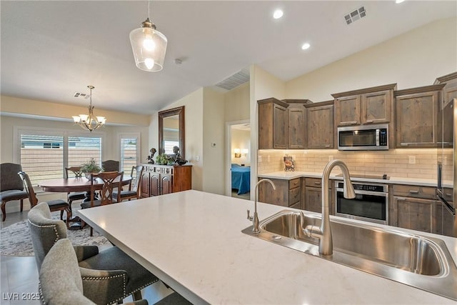 kitchen featuring visible vents, lofted ceiling, decorative backsplash, stainless steel appliances, and a sink