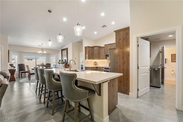 kitchen featuring a kitchen bar, visible vents, a sink, light countertops, and decorative backsplash