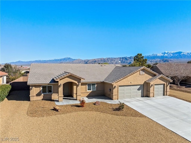 ranch-style house featuring stucco siding, a mountain view, concrete driveway, an attached garage, and a tiled roof