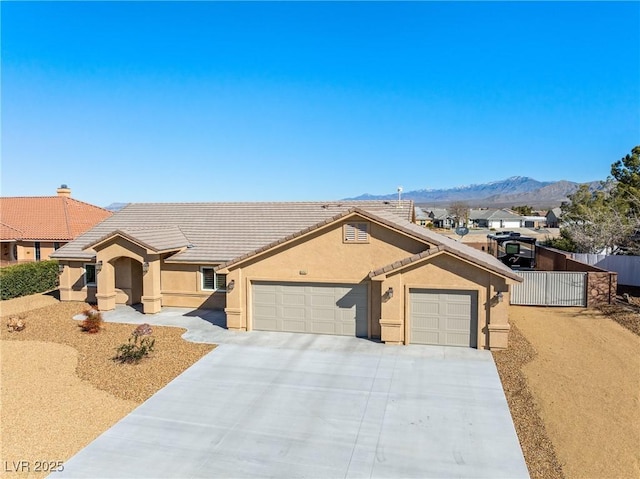 ranch-style home featuring stucco siding, a tile roof, fence, a mountain view, and an attached garage