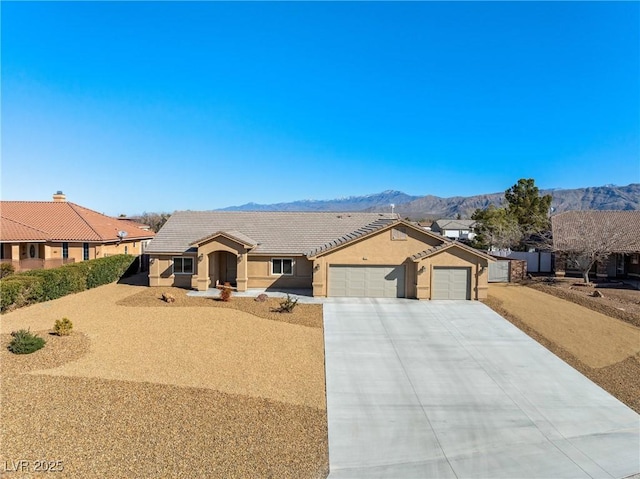 ranch-style house with an attached garage, concrete driveway, a mountain view, and stucco siding